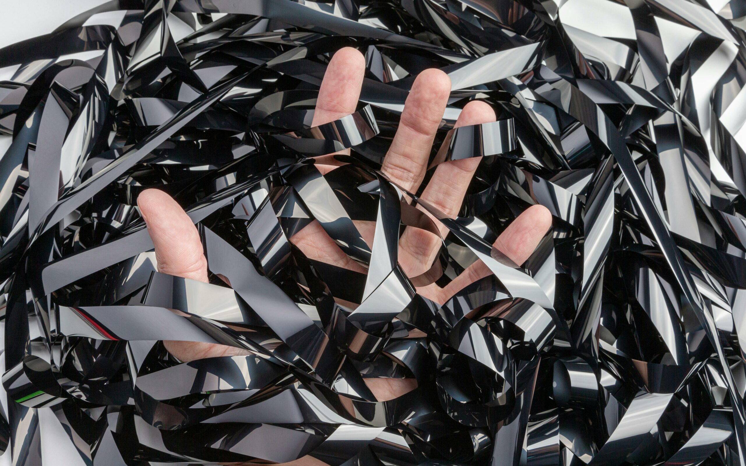 A hand tangled in a chaotic mess of analog film tape, symbolizing creative expression.